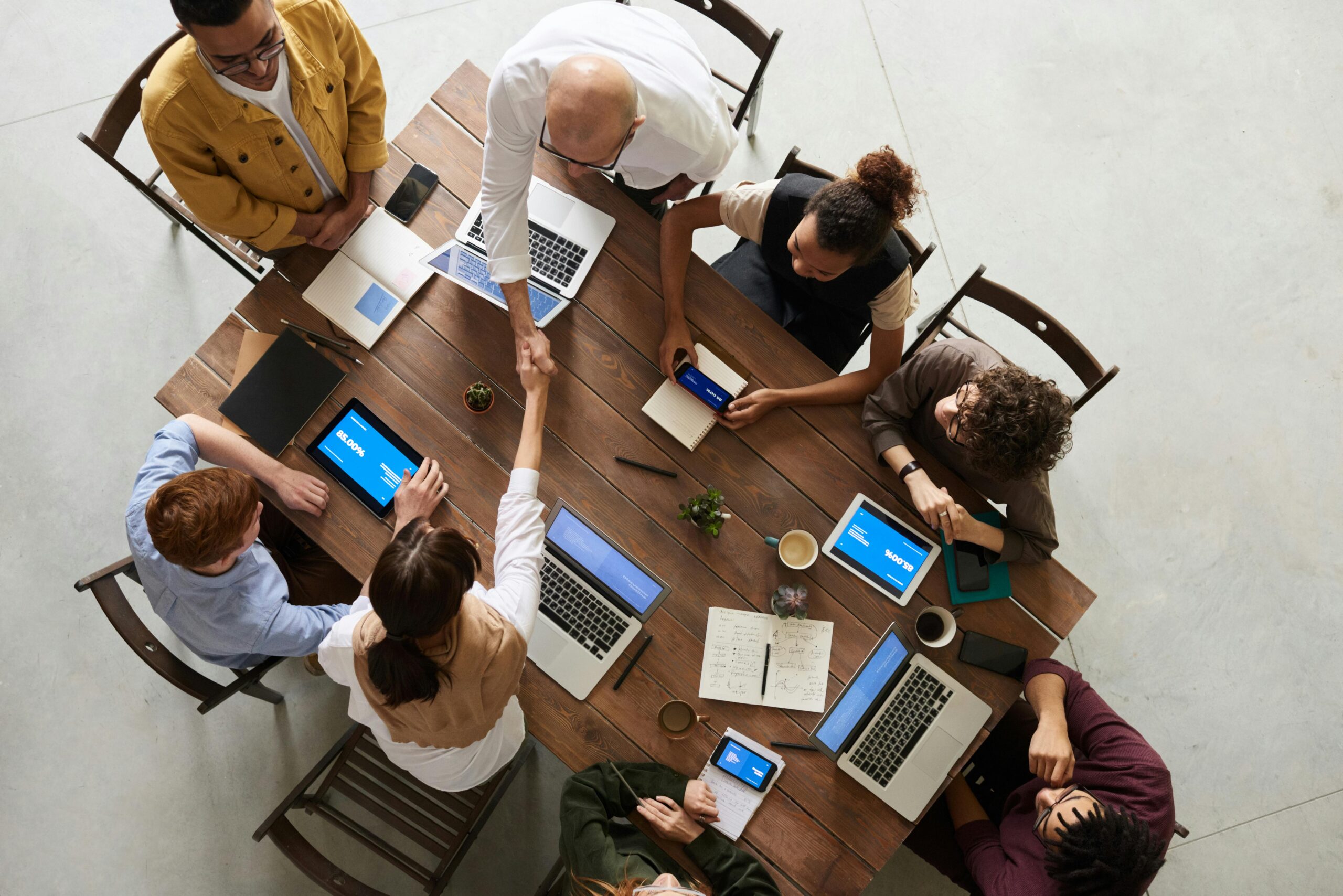 Home Top view of a diverse team collaborating in an office setting with laptops and tablets, promoting cooperation.